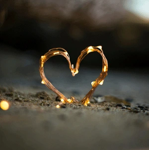 Heart made of fairy lights in sand